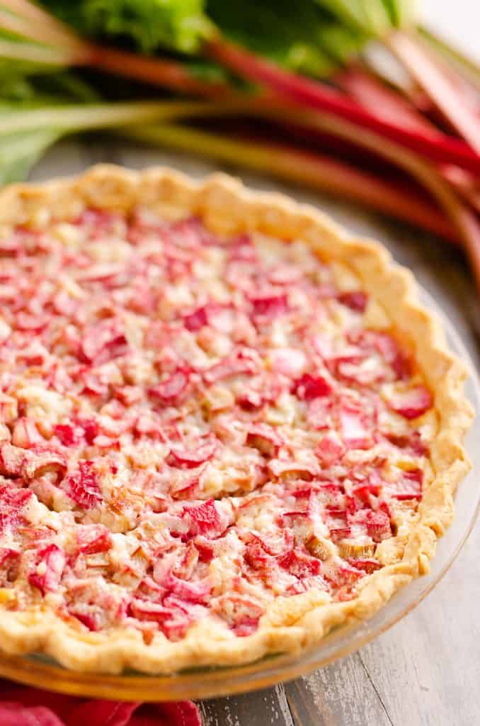 Rhubarb Custard Pie on table with stalks of rhubarb