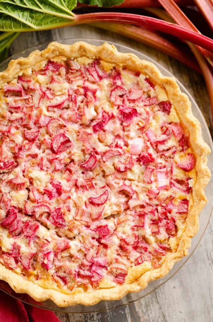 Rhubarb Custard Pie on table with stalks of rhubarb