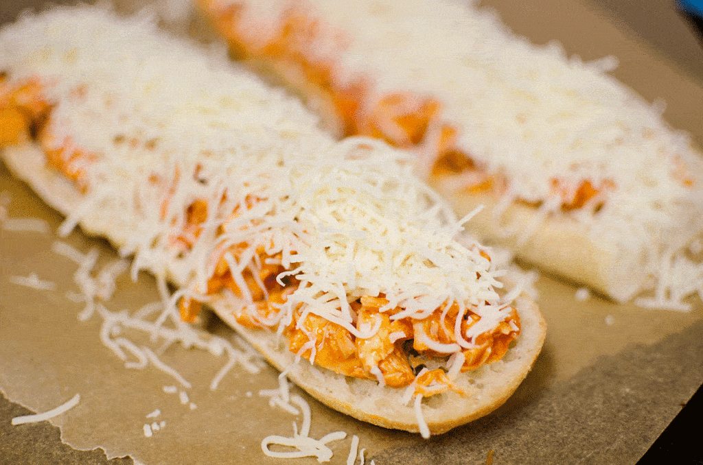 french bread topped wtih buffalo chicken and shredded cheese