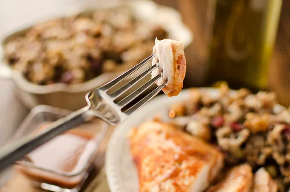 bite of turkey on fork dipped in crock pot cranberry sauce