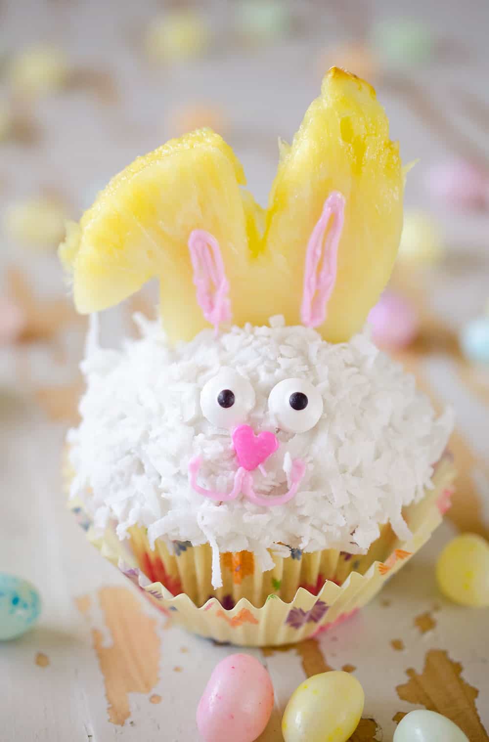 Light Coconut Cream Easter Bunny Cupcakes are a fun and healthy spring dessert recipe. Lightened up cupcakes are topped with bunny ears made from fruit, for a holiday treat kids and adults will LOVE! #Easter #Cupcakes #Light #Healthy