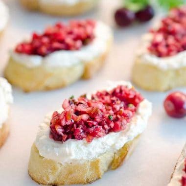 Cranberry Cream Cheese Bruschetta are a fresh twist on a classic appetizer. Toasted french bread is topped with cream cheese and a spicy cranberry salsa for an hors d'oeuvre perfect for any holiday party!