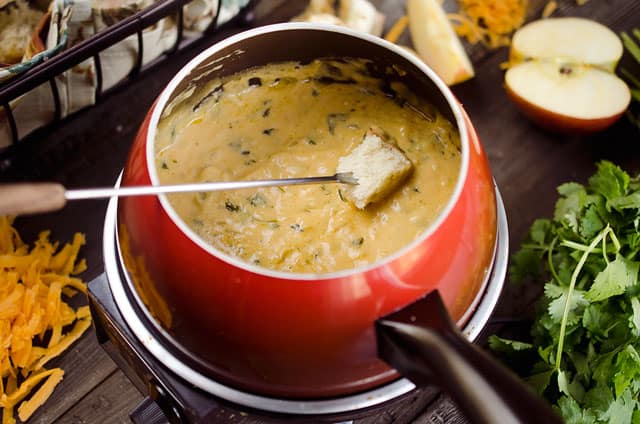 Zesty Cheddar Fondue is an easy and delicious appetizer perfect for the holidays. It is a creamy cheese fondue filled with rich sharp cheddar, onions, garlic and cilantro that pairs perfectly with bread and apples.