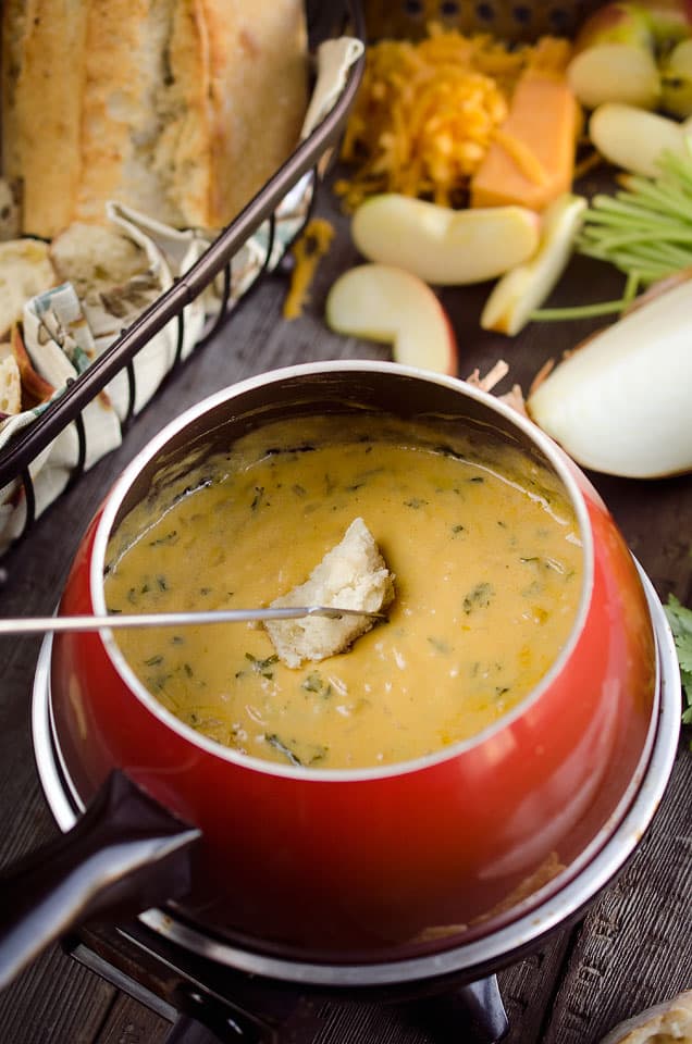 Zesty Cheddar Fondue is an easy and delicious appetizer perfect for the holidays. It is a creamy cheese fondue filled with rich sharp cheddar, onions, garlic and cilantro that pairs perfectly with bread and apples.