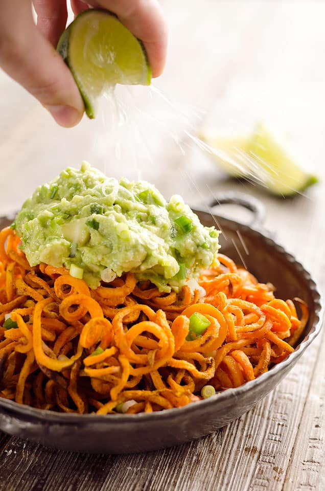 Spicy Roasted Sweet Potato Spirals with Guacamole is an amazingly delicious meatless dinner or appetizer with crispy sweet potatoes coated in garlic & chili powder and topped with a zesty guacamole. 