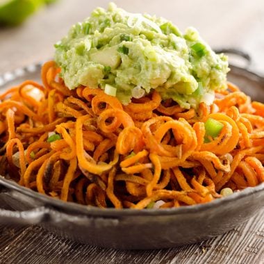 Spicy Roasted Sweet Potato Spirals with Guacamole is an amazingly delicious meatless dinner or appetizer with crispy sweet potatoes coated in garlic & chili powder and topped with a zesty guacamole.