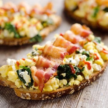 Sriracha Bacon Bleu Cheese Breakfast Toasts are a light meal bursting with bold and spicy flavors. Fluffy scrambled eggs and spinach are piled on whole wheat toast and topped with a slice of bacon, bleu cheese crumbles and sriracha for a breakfast you won't soon forget!