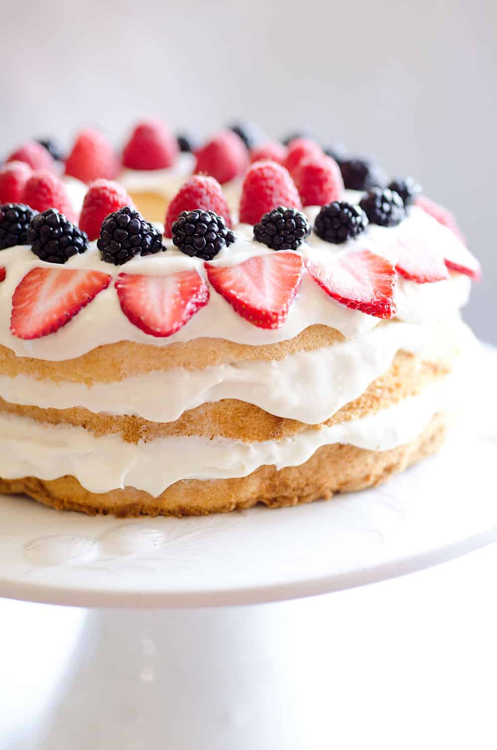 Light Berry Angel Food Cake is an easy and delicious 15 minute dessert. Angel food cake is layered with luscious white chocolate Cool Whip and topped with fresh berries for a guilt-free treat!