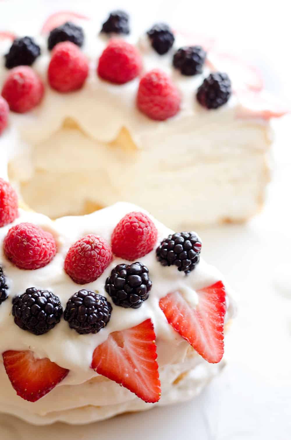 Light Berry Angel Food Cake is an easy and delicious 15 minute dessert. Angel food cake is layered with luscious white chocolate Cool Whip and topped with fresh berries for a guilt-free treat!