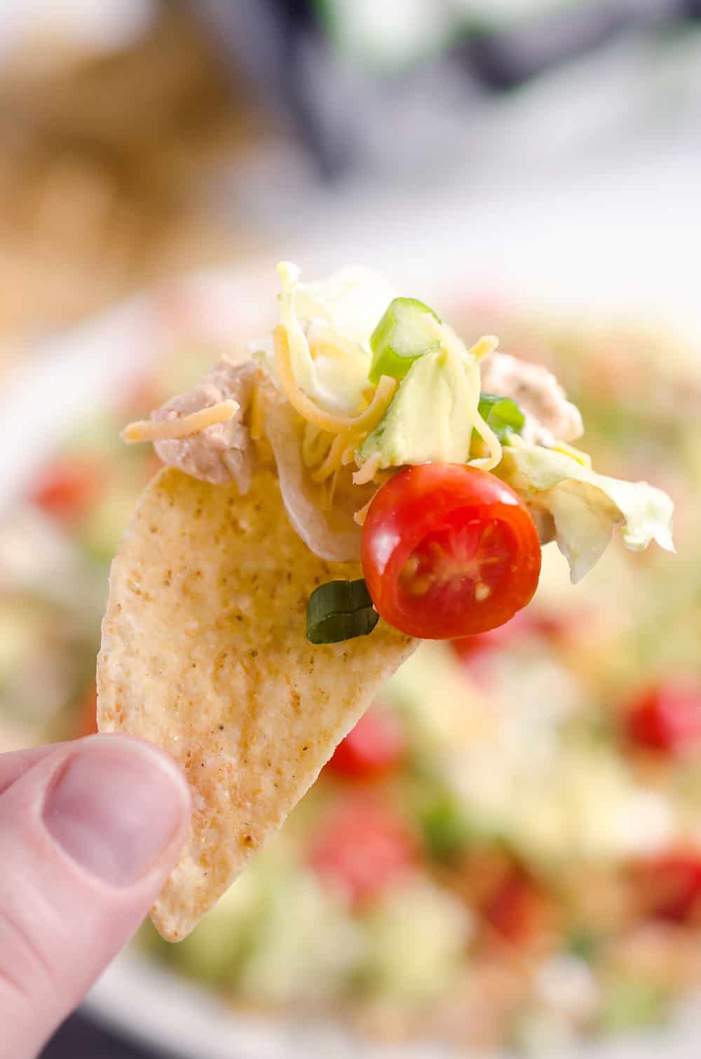 Skinny Taco Dip is a light and zesty appetizer that is a serious crowd-pleaser! This easy snack is lightened up with Greek yogurt, salsa and light cream cheese and topped with healthy avocado, tomatoes and green onions! Serve with your favorite chips for a treat everyone will love.