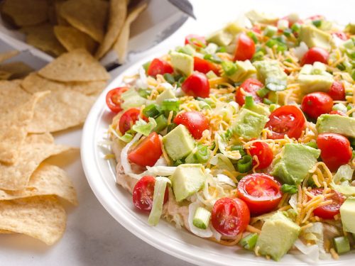 Skinny Taco Dip is a light and zesty appetizer that is a serious crowd-pleaser! This easy snack is lightened up with Greek yogurt, salsa and light cream cheese and topped with healthy avocado, tomatoes and green onions! Serve with your favorite chips for a treat everyone will love.