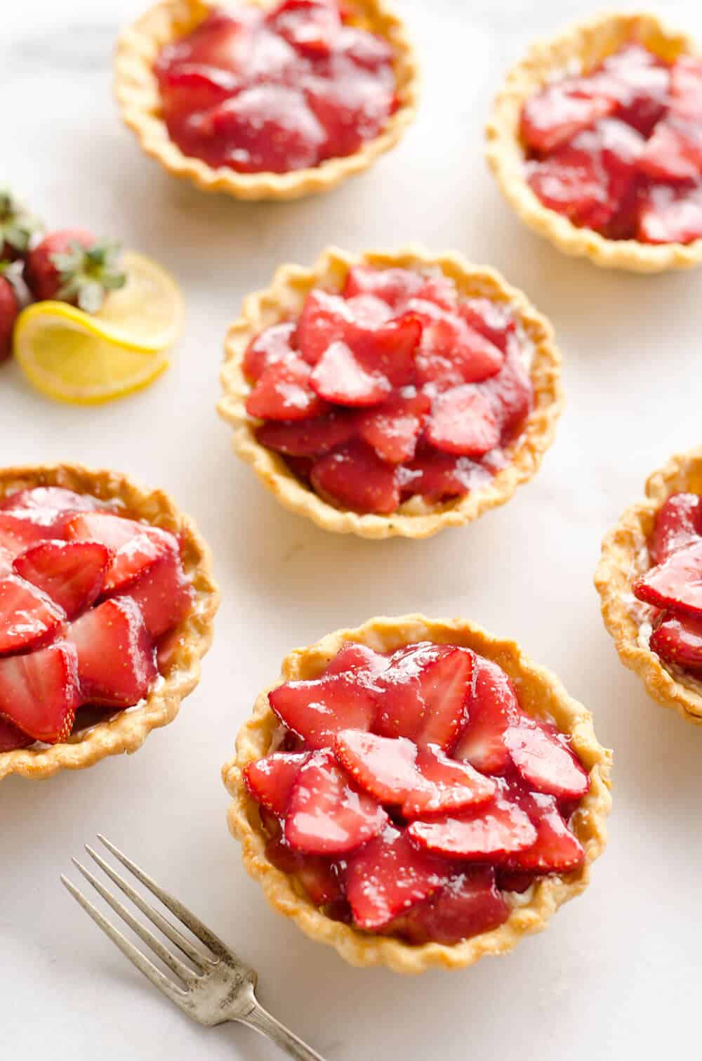 Mini Strawberry Lemon Pies are the perfect dessert recipe to serve your party guests for an individual sweet they will love! A flaky pie crust is topped with a lemon cream cheese layer, fresh strawberries and a sweet strawberry lemon sauce for tons of great flavor and texture!