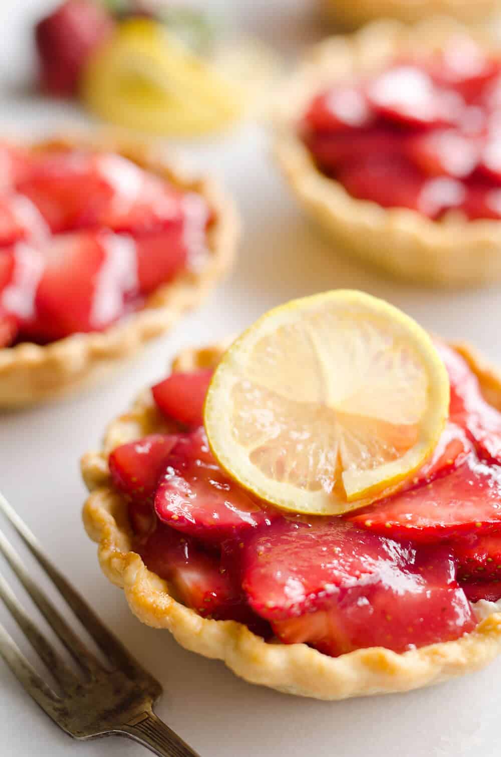 Mini Strawberry Lemon Pies are the perfect dessert recipe to serve your party guests for an individual sweet they will love! A flaky pie crust is topped with a lemon cream cheese layer, fresh strawberries and a sweet strawberry lemon sauce for tons of great flavor and texture!