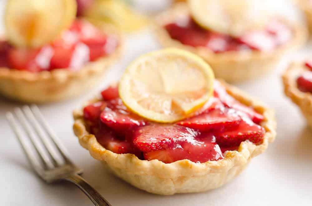 Mini Strawberry Lemon Pies are the perfect dessert recipe to serve your party guests for an individual sweet they will love! A flaky pie crust is topped with a lemon cream cheese layer, fresh strawberries and a sweet strawberry lemon sauce for tons of great flavor and texture!