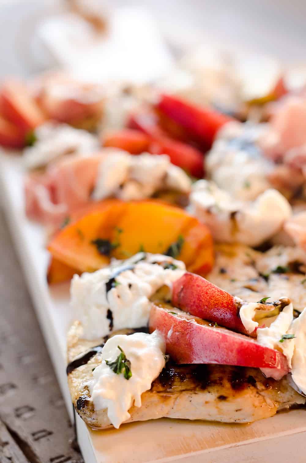 Balsamic Chicken with Peaches & Prosciutto is a deliciously simple and healthy dinner made on the grill in just 10 minutes! Grilled chicken is topped with fresh peaches and burrata cheese and finished off with a balsamic reduction and basil for a combination of flavors you will love. 