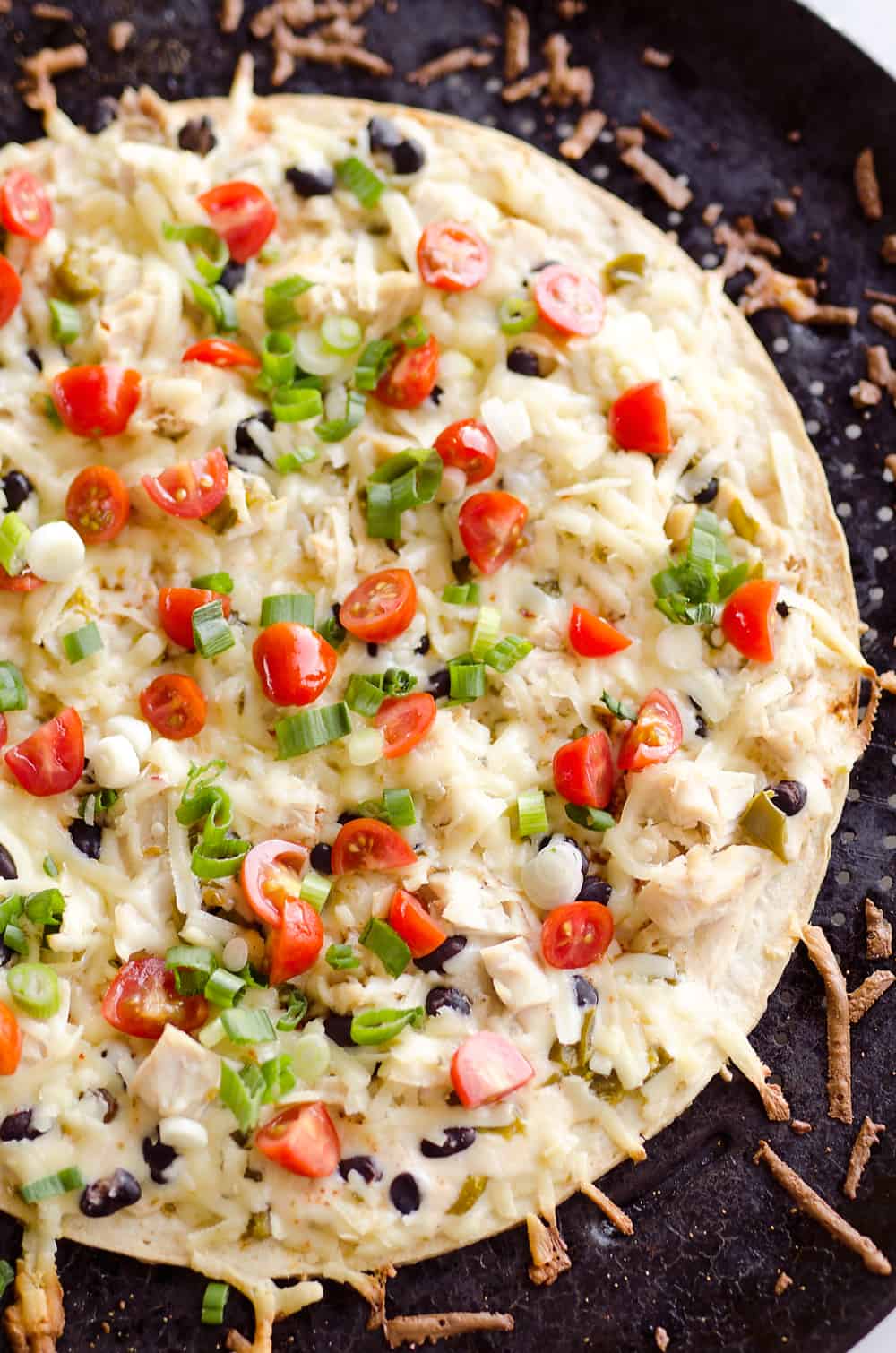 Light & Spicy Southwest Chicken Pizza is an easy recipe bursting with bold and spicy flavors. A thin and crispy crust is topped with shredded chicken, black beans and jalapeños and finished off with pepper jack cheese, fresh tomatoes and green onions for a delicious weeknight dinner idea.