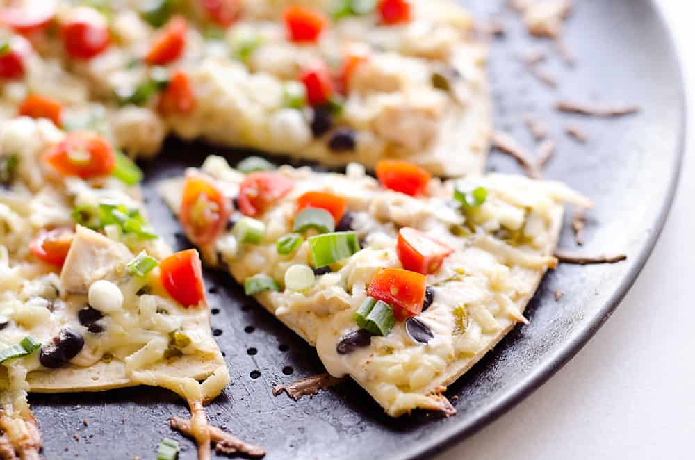 Light & Spicy Southwest Chicken Pizza is an easy recipe bursting with bold and spicy flavors. A thin and crispy crust is topped with shredded chicken, black beans and jalapeños and finished off with pepper jack cheese, fresh tomatoes and green onions for a delicious weeknight dinner idea.