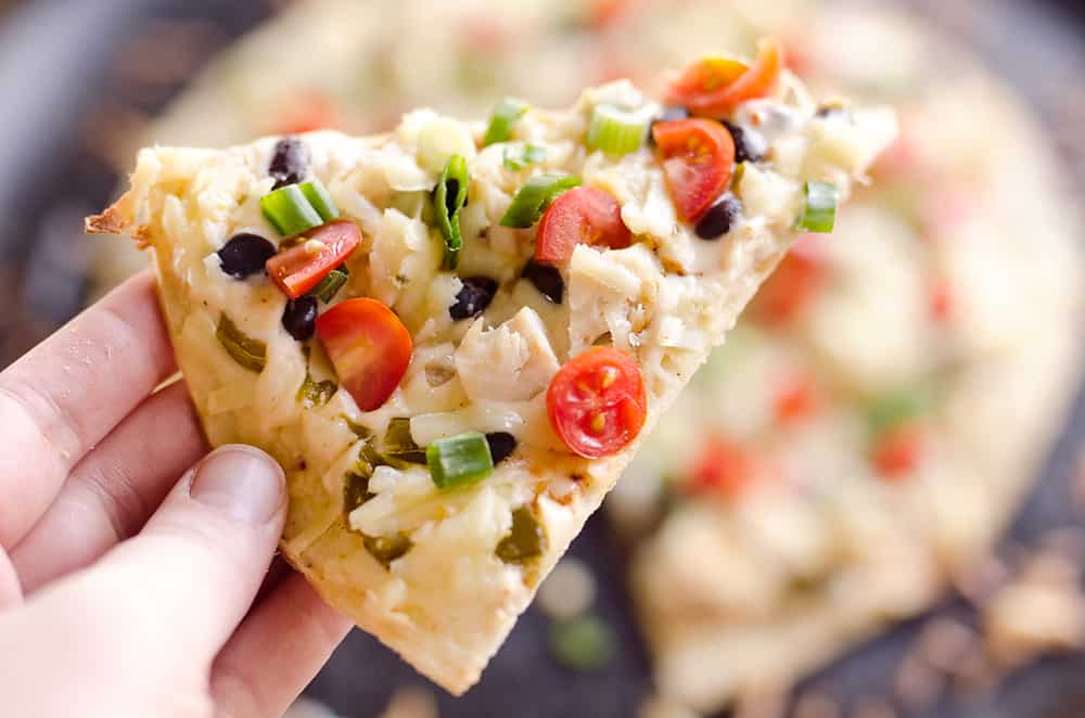 Light & Spicy Southwest Chicken Pizza is an easy recipe bursting with bold and spicy flavors. A thin and crispy crust is topped with shredded chicken, black beans and jalapeños and finished off with pepper jack cheese, fresh tomatoes and green onions for a delicious weeknight dinner idea.