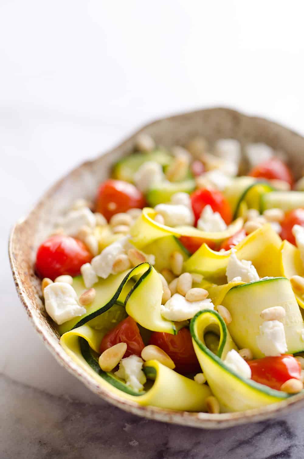 Ribboned Squash & Zucchini Salad is a fresh and healthy vegetarian salad with light veggies, toasted pine nuts, creamy goat cheese and balsamic glaze. Pair it with some grilled shrimp or chicken for an amazing and flavorful dinner you won't forget!