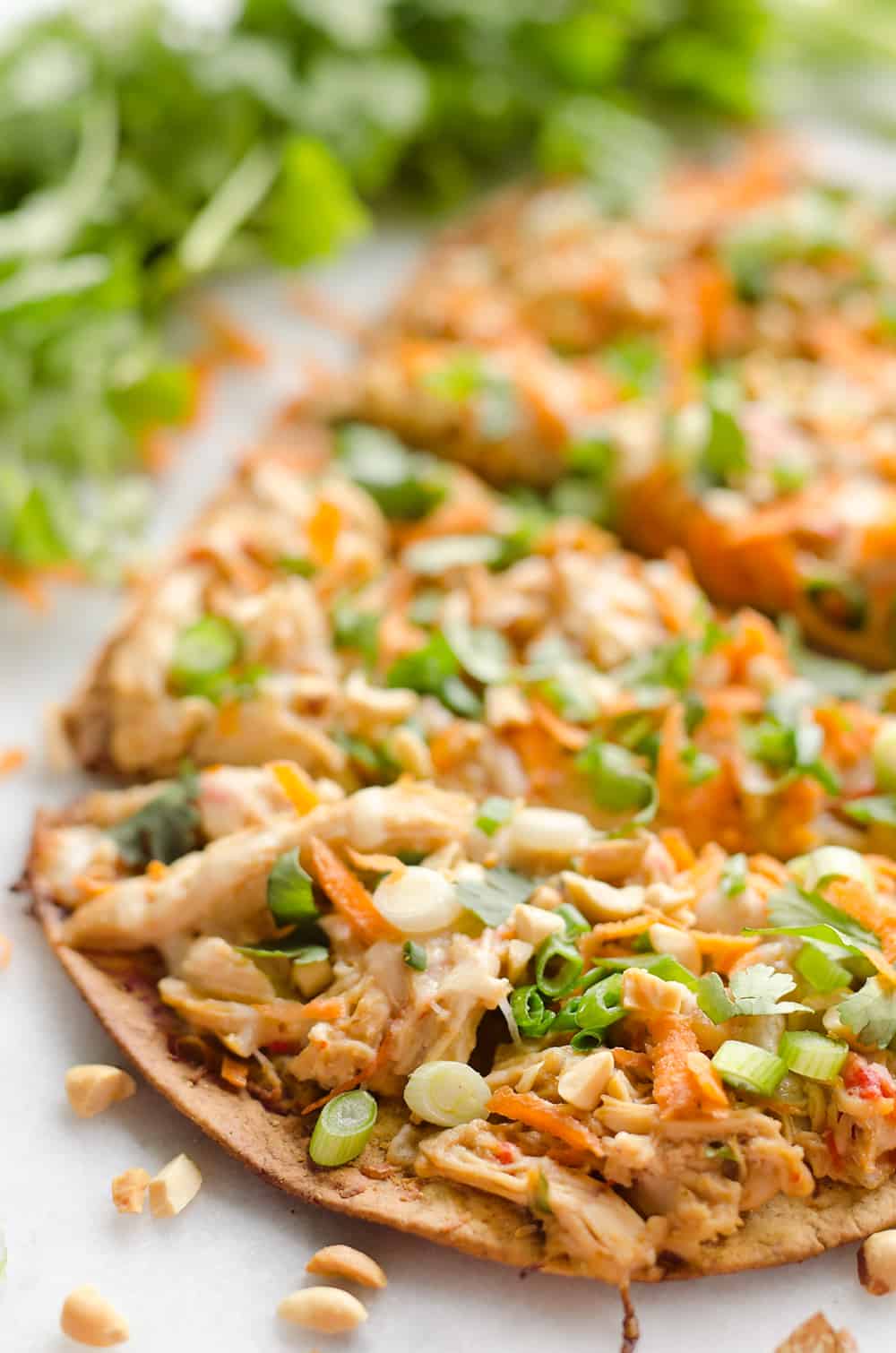 Light Thai Peanut Chicken Flatbread is a quick and healthy recipe perfect for a weeknight dinner! A thin and crispy flatbread is topped with Crock Pot Thai Peanut Chicken, cheese and crunchy vegetables and peanuts! 