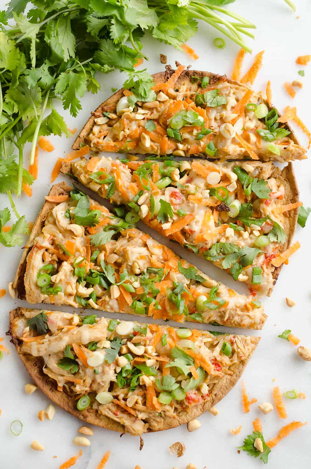 Light Thai Peanut Chicken Flatbread is a quick and healthy recipe perfect for a weeknight dinner! A thin and crispy flatbread is topped with Crock Pot Thai Peanut Chicken, cheese and crunchy vegetables and peanuts! 