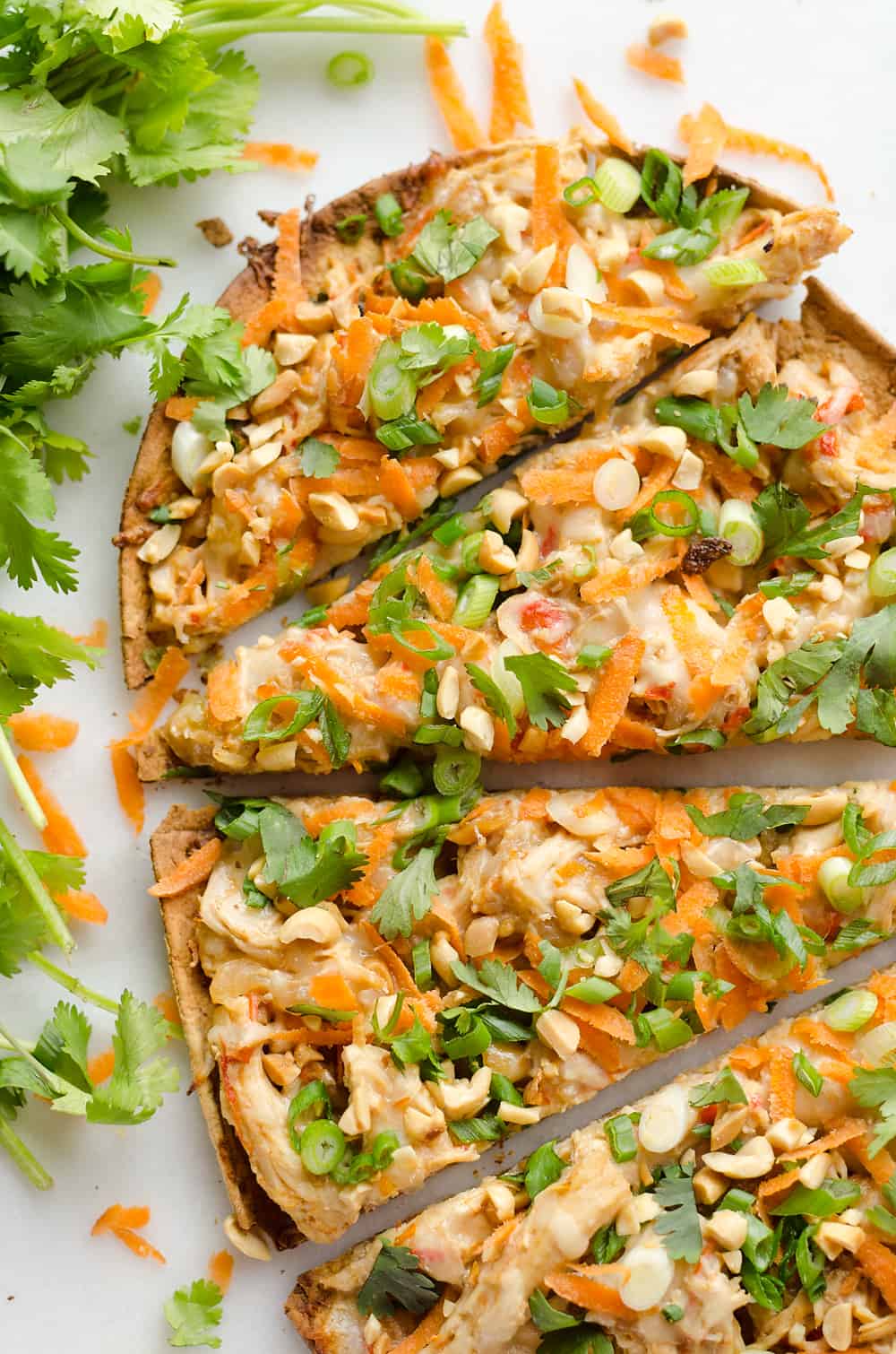 Light Thai Peanut Chicken Flatbread is a quick and healthy recipe perfect for a weeknight dinner! A thin and crispy flatbread is topped with Crock Pot Thai Peanut Chicken, cheese and crunchy vegetables and peanuts! 