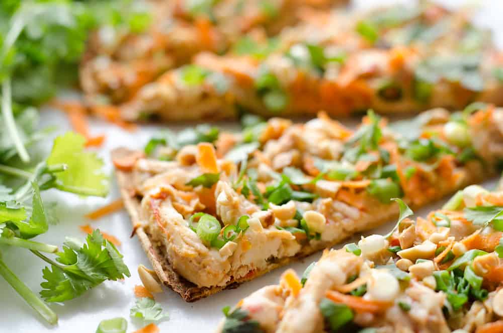 Light Thai Peanut Chicken Flatbread is a quick and healthy recipe perfect for a weeknight dinner! A thin and crispy flatbread is topped with Crock Pot Thai Peanut Chicken, cheese and crunchy vegetables and peanuts! 