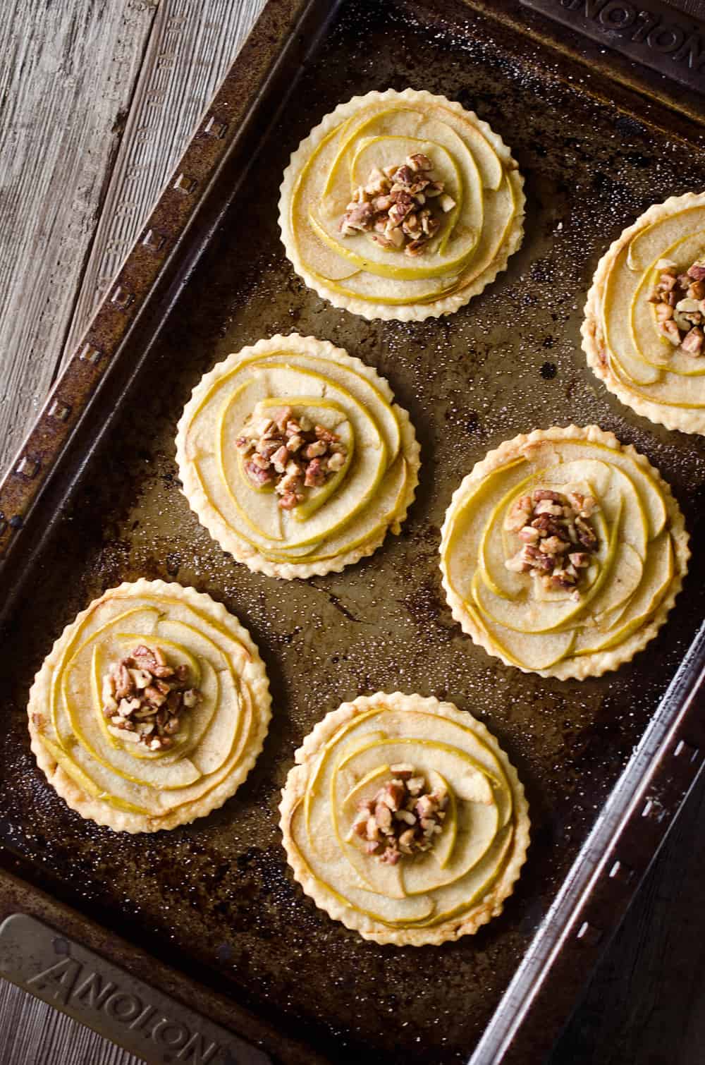 Mini Apple & Browned Butter Tarts are a perfectly light treat with great fall flavors! This dessert includes a flaky pie crust topped with apples and pecans and finished off with decadent browned butter for a bite-sized sweet perfect for holiday parties.