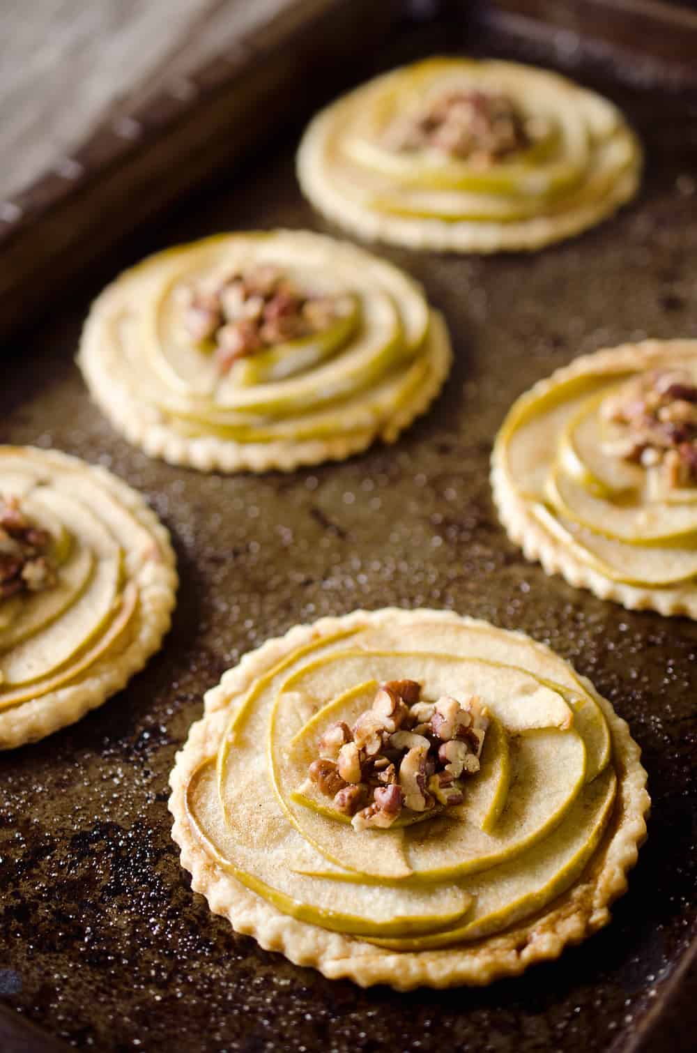 Mini Apple & Browned Butter Tarts are a perfectly light treat with great fall flavors! This dessert includes a flaky pie crust topped with apples and pecans and finished off with decadent browned butter for a bite-sized sweet perfect for holiday parties.