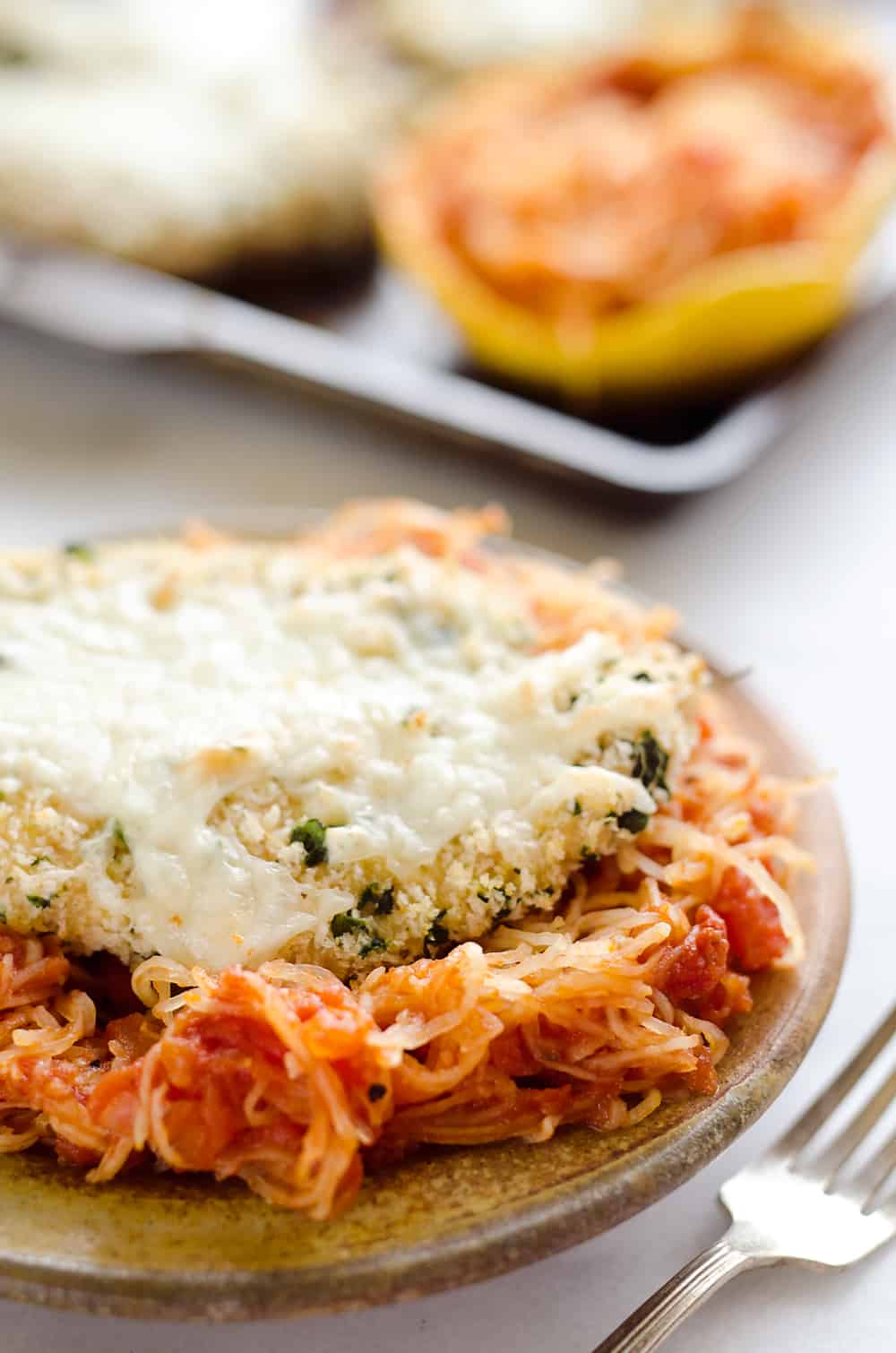 Skinny Spaghetti Squash Chicken Parmesan is a healthy twist on the traditional classic. Lightly breaded chicken breasts are baked and served with low-carb spaghetti squash and marinara sauce for a comforting dinner your family will ask for again and again!