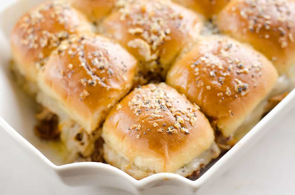 Cheesy BBQ Pork Baked Sliders são uma refeição fácil e familiar que vai querer fazer repetidamente! O BBQ de Cozedor de Pressão Puxado de Porco e queijo Havarti cremoso é em camadas nos pães havaianos e coberto com um molho de manteiga saboroso para um jantar que é absolutamente digno de baba.