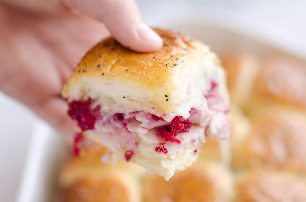 Cheesy Cranberry Turkey Baked Sliders are a quick and easy recipe to use up some of that leftover turkey and cranberries from the holidays! Hawaiian rolls are topped with turkey, cranberries and Havarti cheese and topped with a savory butter sauce for a great dinner after the big meal. 