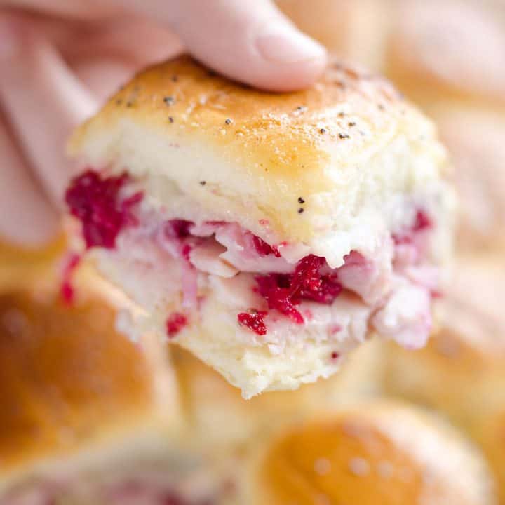 Cheesy Cranberry Turkey Baked Sliders held in hand over baking pan