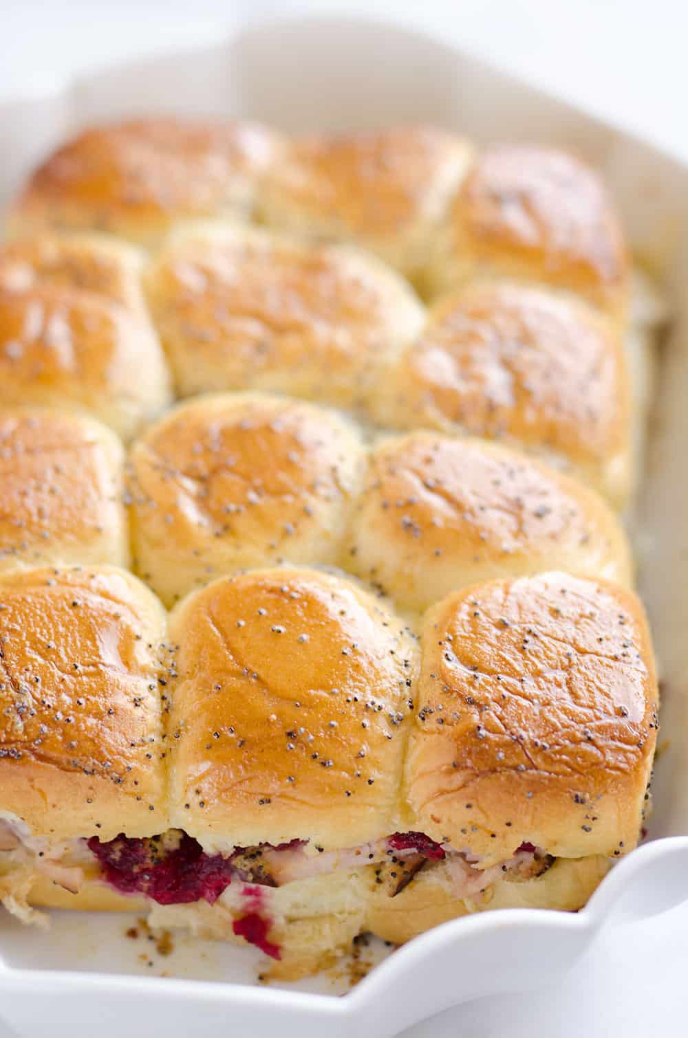 Cheesy Cranberry Turkey Baked Sliders are a quick and easy recipe to use up some of that leftover turkey and cranberries from the holidays! Hawaiian rolls are topped with turkey, cranberries and Havarti cheese and topped with a savory butter sauce for a great dinner after the big meal. 