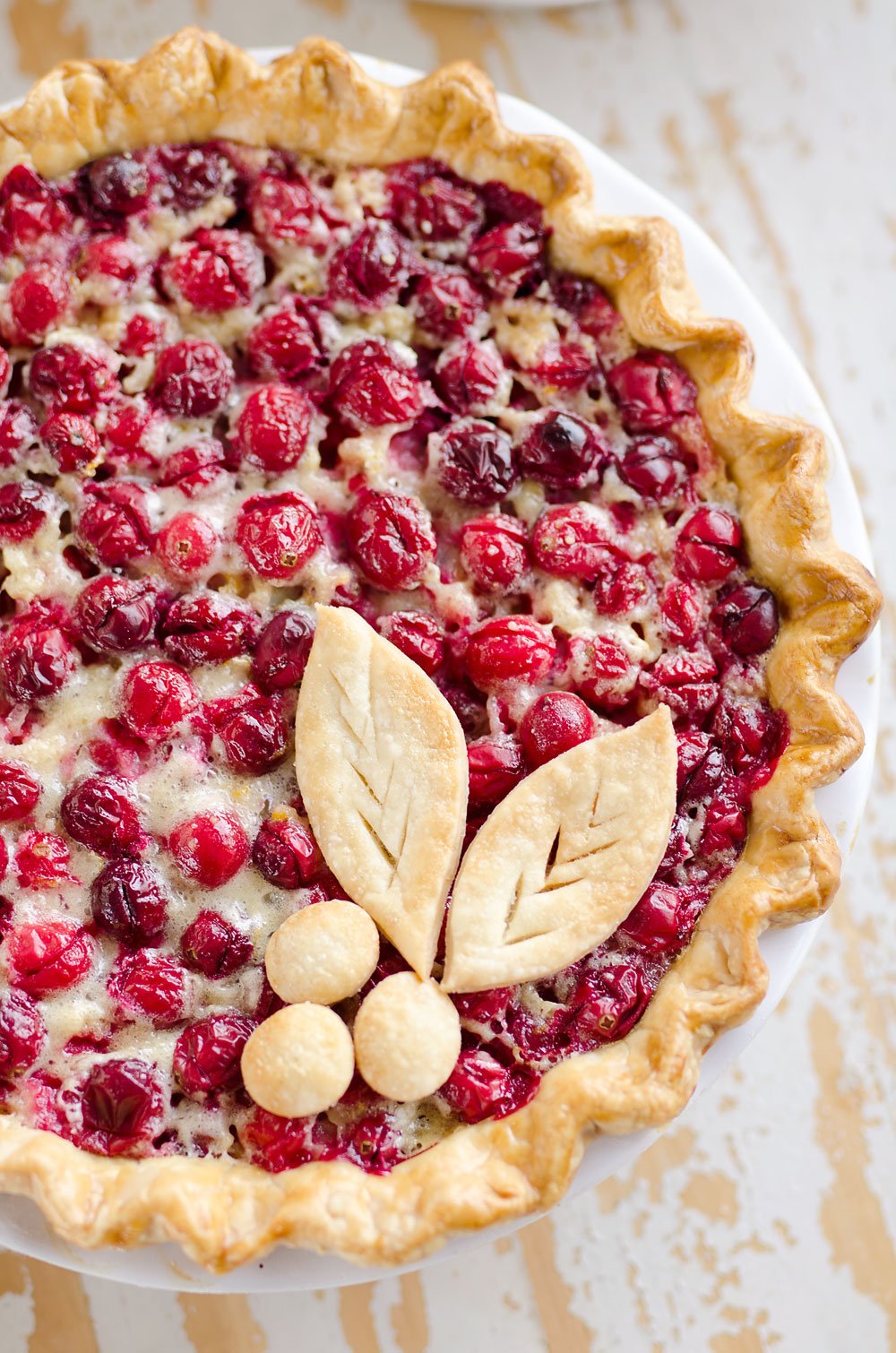Cranberry Orange Custard Pie is a festive and unique pie to enjoy during the holiday season. Silky sweet custard laced with orange zest and tart cranberries fill a flaky pie crust for a delicious dessert you will love!