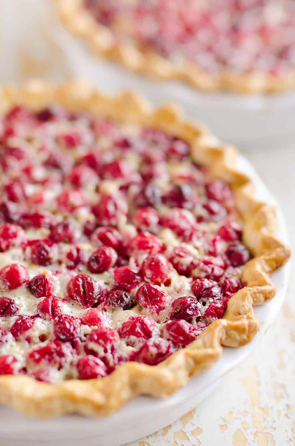 Cranberry Orange Custard Pie is a festive and unique pie to enjoy during the holiday season. Silky sweet custard laced with orange zest and tart cranberries fill a flaky pie crust for a delicious dessert you will love!