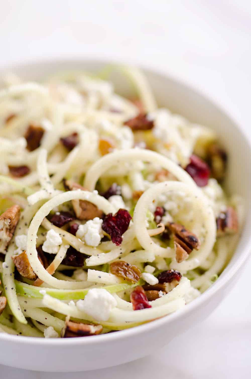 Spiralized Apple Cranberry Salad is an easy and healthy recipe made with crunchy apples, cranberries, pecans and goat cheese all tossed in a light Citrus Poppy Seed Dressing. This salad makes for a a deliciously easy side dish or vegetarian entree you will love!