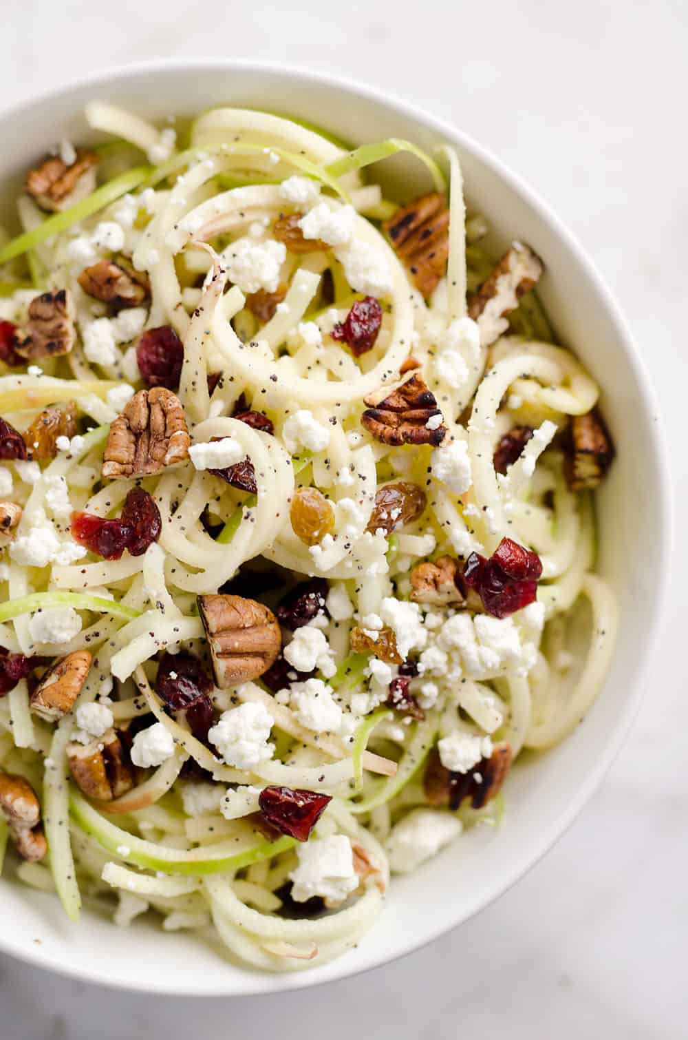 Spiralized Apple Cranberry Salad is an easy and healthy recipe made with crunchy apples, cranberries, pecans and goat cheese all tossed in a light Citrus Poppy Seed Dressing. This salad makes for a a deliciously easy side dish or vegetarian entree you will love!