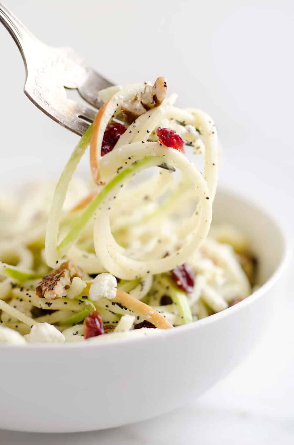 Spiralized Apple Cranberry Salad is an easy and healthy recipe made with crunchy apples, cranberries, pecans and goat cheese all tossed in a light Citrus Poppy Seed Dressing. This salad makes for a a deliciously easy side dish or vegetarian entree you will love!