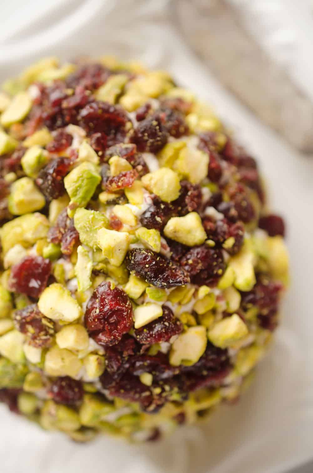 Cranberry Pistachio Cheese Ball is a festive red and green appetizer fantastic for the holidays! A cream cheese and cranberry mixture is rolled in salty pistachios and served with your favorite crackers for the perfect party food. 