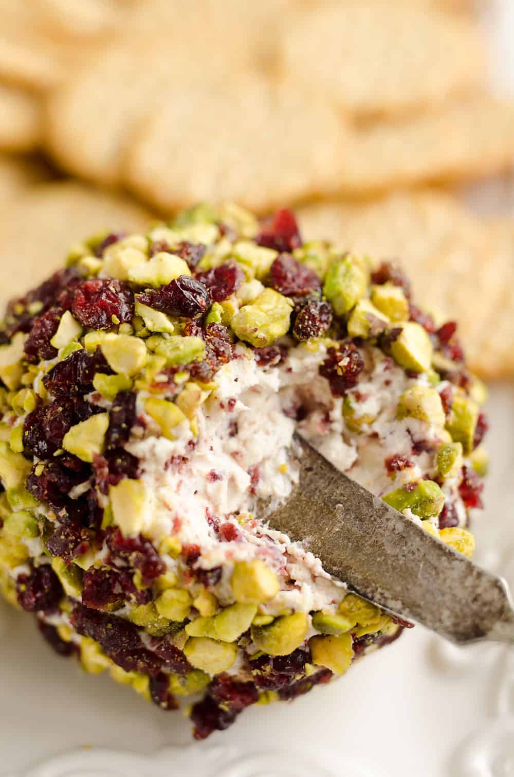 Cranberry Pistachio Cheese Ball is a festive red and green appetizer fantastic for the holidays! A cream cheese and cranberry mixture is rolled in salty pistachios and served with your favorite crackers for the perfect party food. 