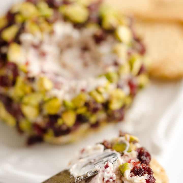 Cranberry Pistachio Cheese Ball is a festive red and green appetizer fantastic for the holidays! A cream cheese and cranberry mixture is rolled in salty pistachios and served with your favorite crackers for the perfect party food.