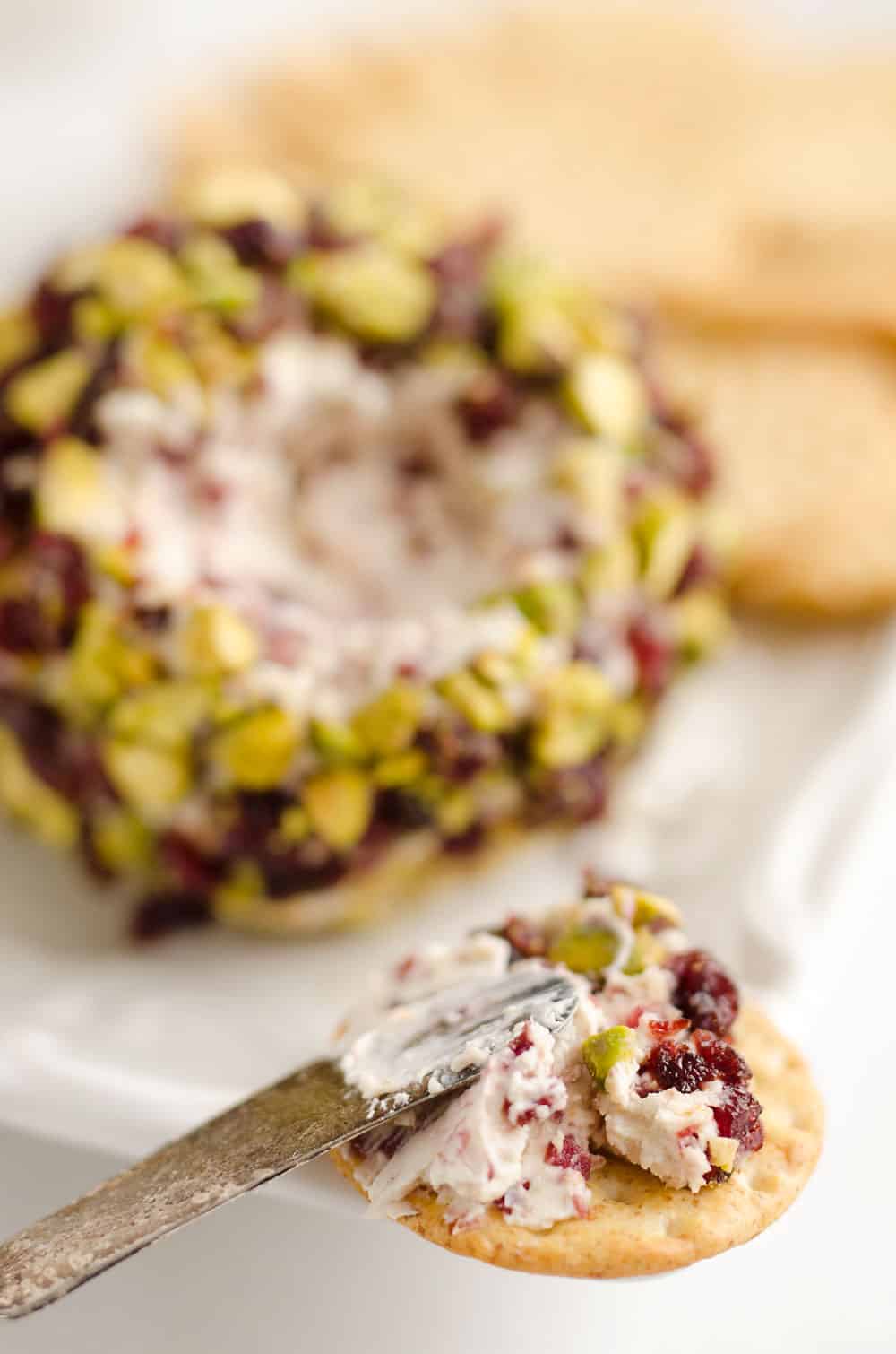 Cranberry Pistachio Cheese Ball is a festive red and green appetizer fantastic for the holidays! A cream cheese and cranberry mixture is rolled in salty pistachios and served with your favorite crackers for the perfect party food. 