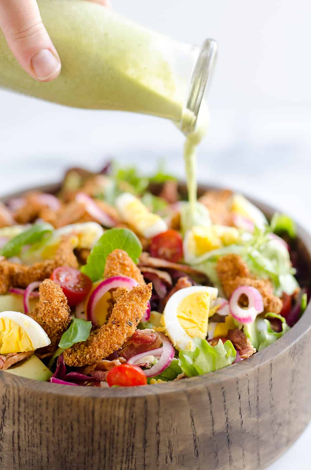 Crispy Chicken & Avocado Cobb Salad is an easy 20 minute salad recipe made in your Airfryer with Gold'n Plump Chipotle Adobo SHAKERS, bacon, veggies, lightly pickled onions and a creamy Avocado Lime Green Goddess Sauce. This hearty salad is a healthy dinner idea bursting with bold flavor and crunch!