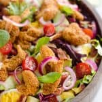 Crispy Chicken & Avocado Cobb Salad is an easy 20 minute salad recipe made in your Airfryer with Gold'n Plump Chipotle Adobo SHAKERS, bacon, veggies, lightly pickled onions and a creamy Avocado Lime Green Goddess Sauce. This hearty salad is a healthy dinner idea bursting with bold flavor and crunch!