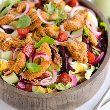 Crispy Chicken & Avocado Cobb Salad is an easy 20 minute salad recipe made in your Airfryer with Gold'n Plump Chipotle Adobo SHAKERS, bacon, veggies, lightly pickled onions and a creamy Avocado Lime Green Goddess Sauce. This hearty salad is a healthy dinner idea bursting with bold flavor and crunch!