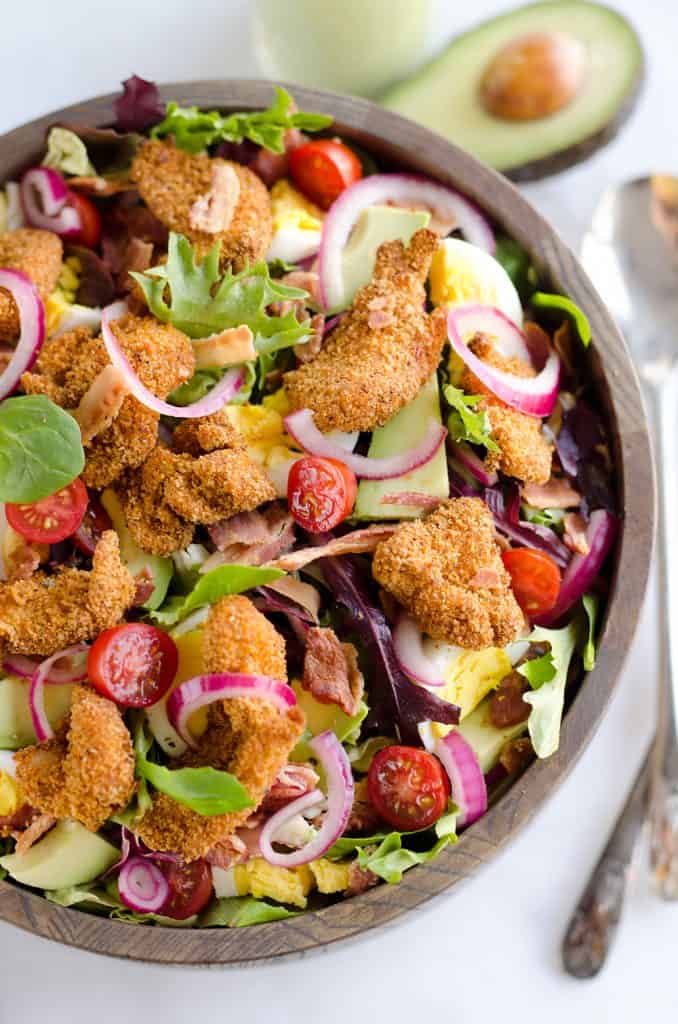 Crispy Chicken & Avocado Cobb Salad is an easy 20 minute salad recipe made in your Airfryer with Gold'n Plump Chipotle Adobo SHAKERS, bacon, veggies, lightly pickled onions and a creamy Avocado Lime Green Goddess Sauce. This hearty salad is a healthy dinner idea bursting with bold flavor and crunch!