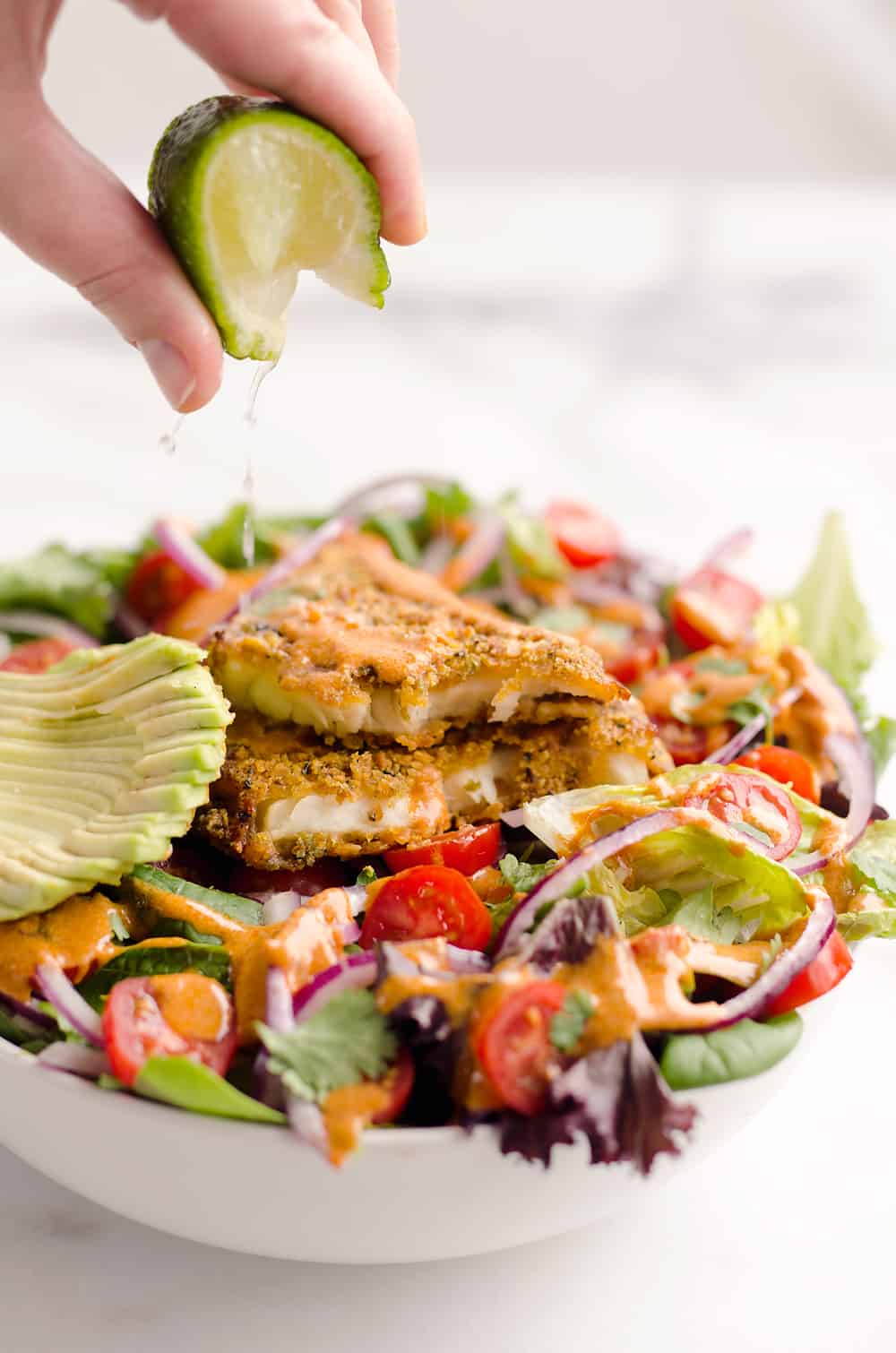 Southwest Tortilla Crusted Tilapia Salad is an easy and healthy dinner idea with a bed of mixed greens topped with tomatoes, avocado, red onion, Tortilla Crusted Tilapia and a homemade Chipotle Lime Dressing.