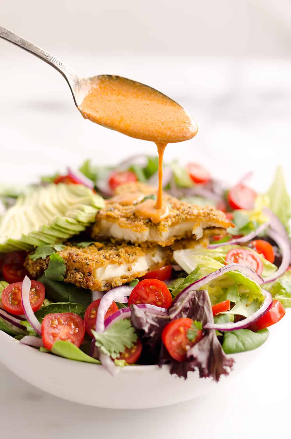 Southwest Tortilla Crusted Tilapia Salad is an easy and healthy dinner idea with a bed of mixed greens topped with tomatoes, avocado, red onion, Tortilla Crusted Tilapia and a homemade Chipotle Lime Dressing. 