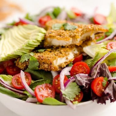 Southwest Tortilla Crusted Tilapia Salad is an easy and healthy dinner idea with a bed of mixed greens topped with tomatoes, avocado, red onion, Tortilla Crusted Tilapia and a homemade Chipotle Lime Dressing.